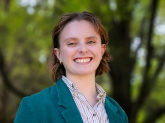 a young white woman wearing a collared shirt and jacket smiles