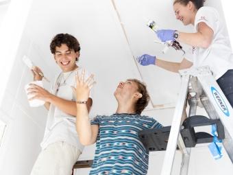 Students on ladder painting and laughing