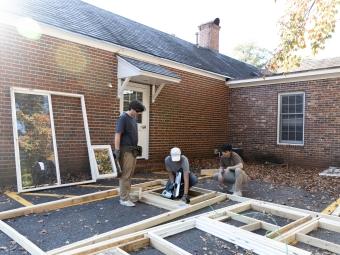 Students building wooden house frame