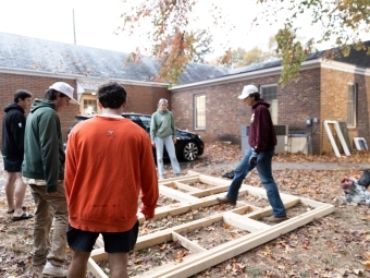 Students standing around frame on ground