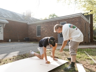 Students measuring construction materials outdoors