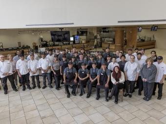 a group of chefs and dining staff pose together in the cafeteria