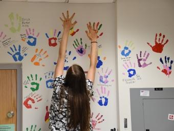 Student painting handprint on wall of Prof. Malcolm Campbell's lab