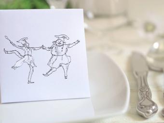 a fancy table set with a notecard of two dancing chefs on the plate
