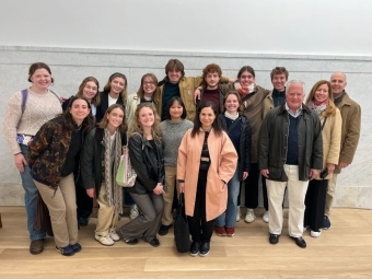 a group of students and a few adults stand together in an art gallery