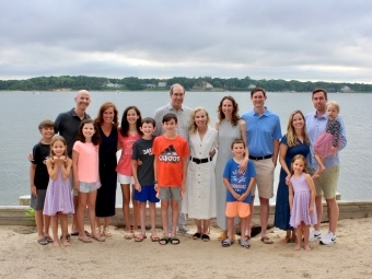 a white family standing in front of a lake on a sandy patch of land