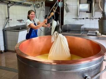 a young white woman makes cheese in a giant vat