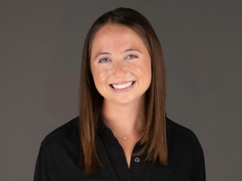 a young white woman smiling while wearing a black collared shirt