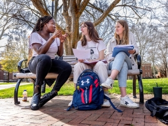 students on a bench on campus talking