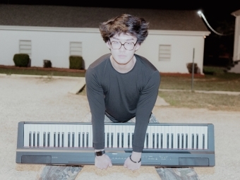 a young Asian man holding a piano