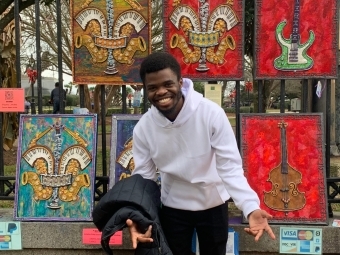 a young man smiling in front of paintings