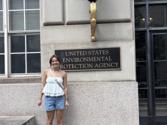 a young white woman stands in front of "US EPA" sign