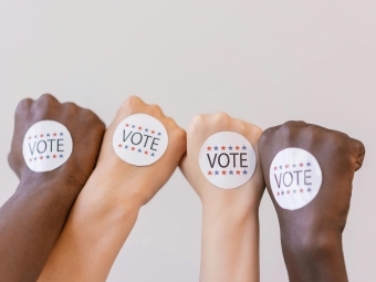 four hands in fists with "vote" stickers