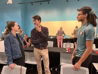 two students talk to an adult in a modern classroom