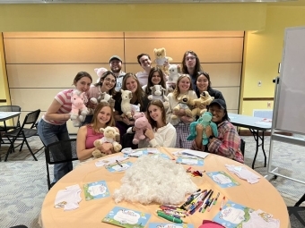 a group of students sit around a table holding stuffed animals