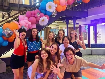 a group of students smiling together in front of a balloon arch