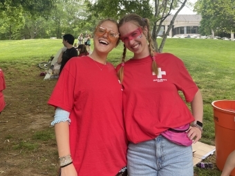 two young women wearing red t-shirts and smile outdoors