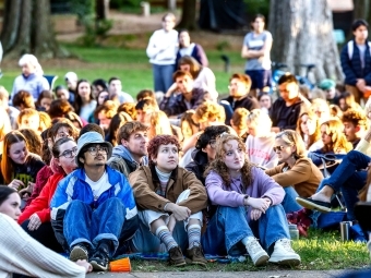 Students sit on the ground, listening intently, at the Phi Eu Debate