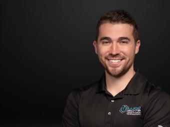 a young white man in a black polo smiling