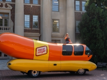 Emily Schmidtt '23 sits atop the Weinermobile in front of the Chambers Building