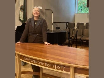 Pastor Mary Katherine Robinson ’93 stands in front of communion table