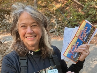 an older white woman smiling while holding postcards