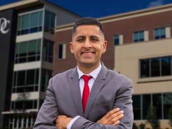 a young man stands in front of a stadium wearing a suit and red tie