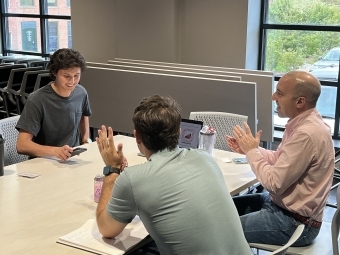 a group of two students with a mentor talking over a table