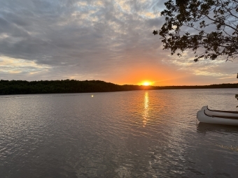 a body of water at sunset with a canoe in the foreground