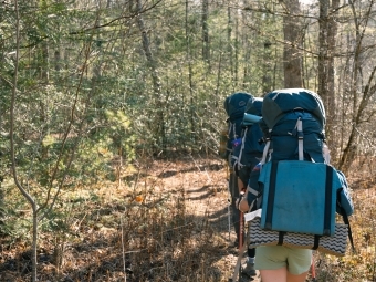 a young woman hiking wearing a backpack in the woods