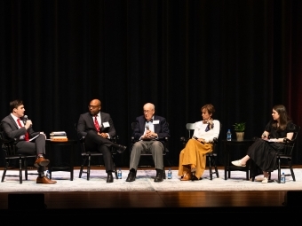 a young man speaks to a panel of alumni on a stage