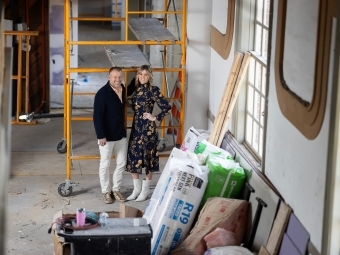 a young white couple stand together in a church under renovation