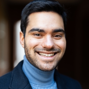 a young man wearing a blue turtleneck and blazer