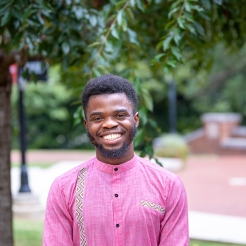 a young Black man wearing pink top