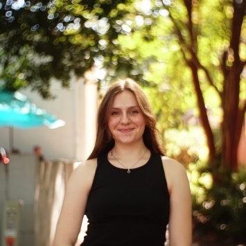 a young woman with light hair wearing a black top outside