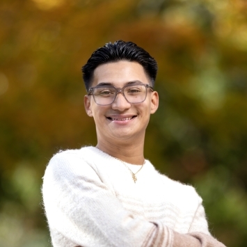 a young man with black hair and glasses wearing a white sweater