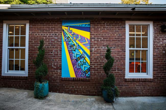 Lula Bell's entryway with graffiti mural and planters against brick exterior