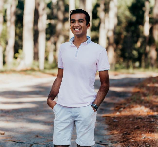 a young man wearing a polo and shorts smiles