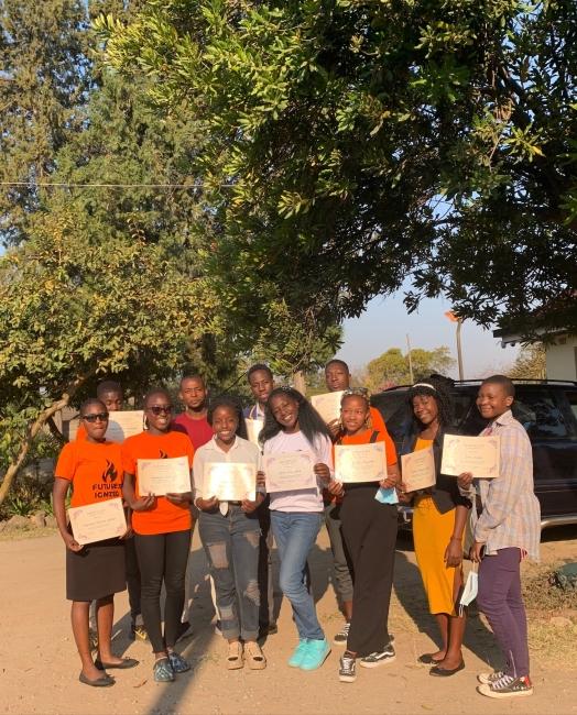 a group of young Black people holding certificates outdoors