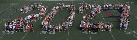 Students stand on a football field formed to say "2027"