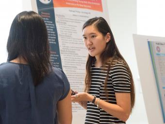 Student presents her poster research to an audience member