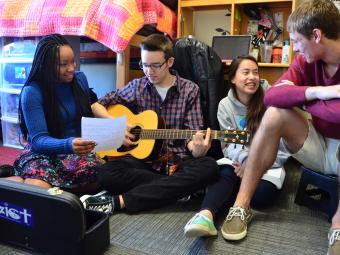 Students hang out in a dorm playing the guitar