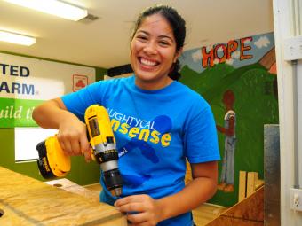 Volunteer holds a drill to plywood inside Habitat offices