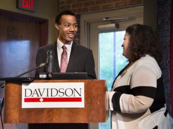 Student stands at podium with Kristin Booher to accept prize